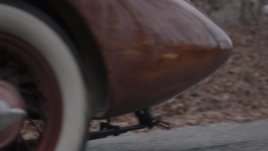 A vintage car drives down a road