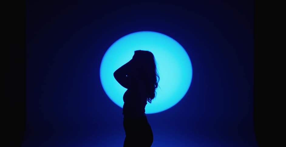 A female performer on a moonlit stage touching her hair