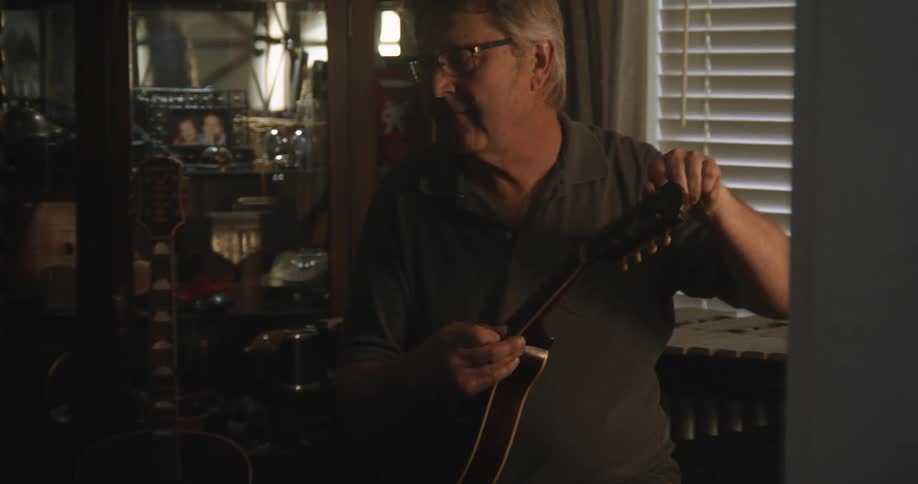 A man adjusts the strings on his ukulele
