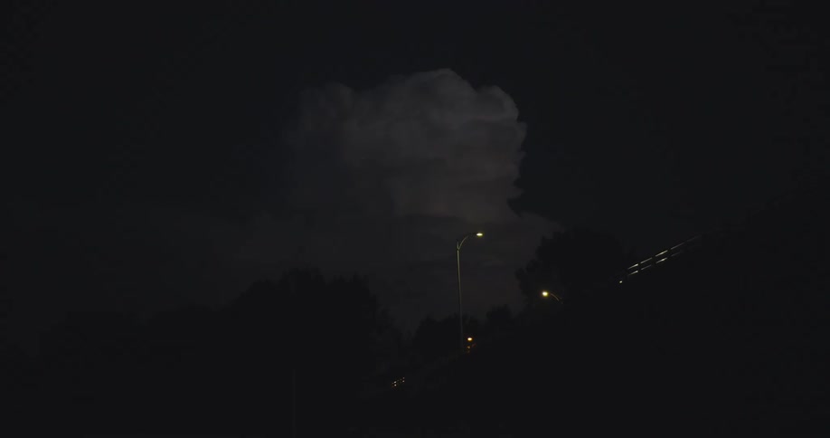 Lightening as a train travels on a bridge at night