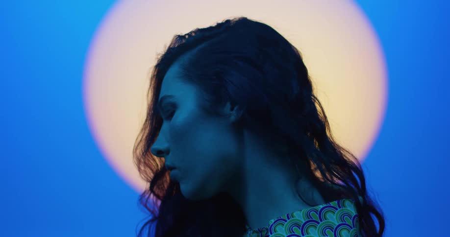 A young woman in a studio is posing with a moon and blue lighting environment