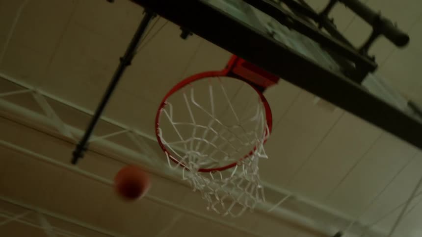 A basketball is tossed into the hoop at a gym
