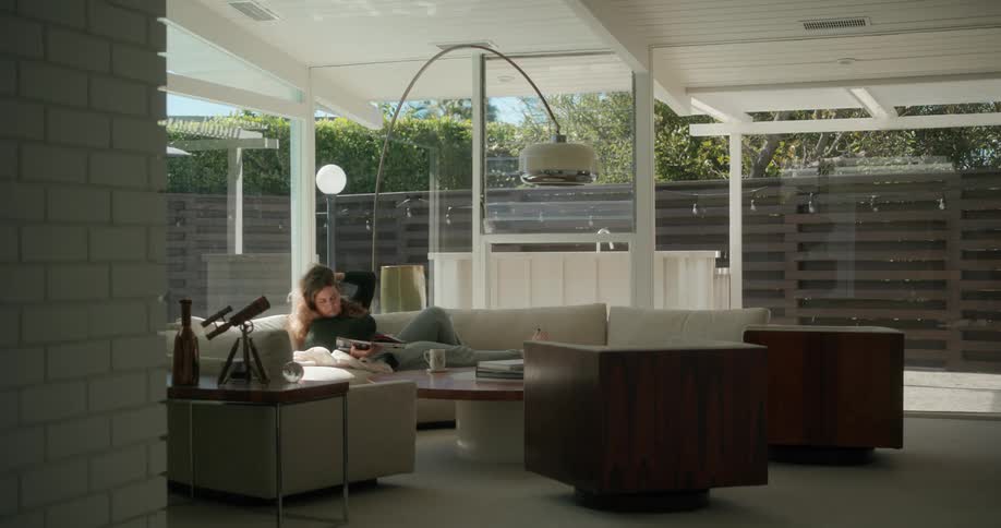 Relaxed woman reclined on a couch at home reading a magazine