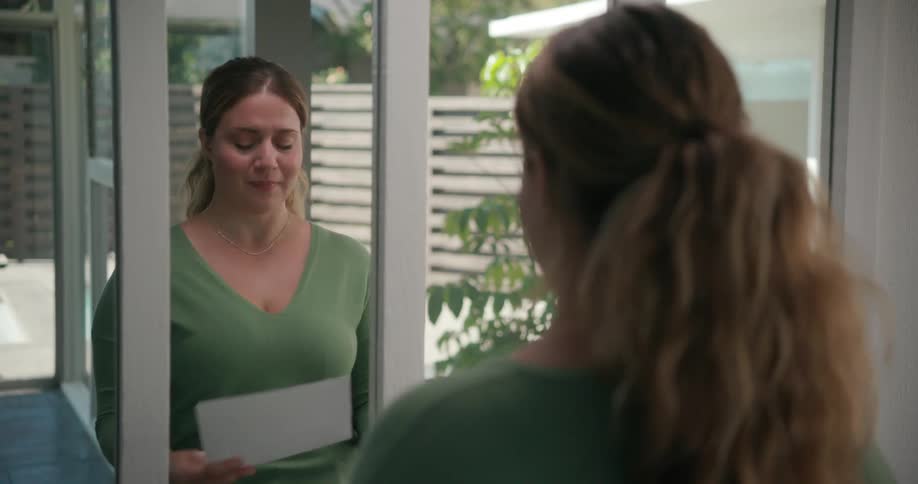 A woman practices speaking in a mirror indoors during the day