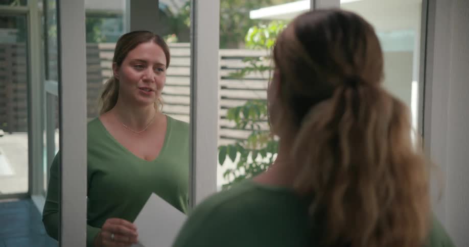 Woman holding a paper and rehearsing her lines in front of a mirror