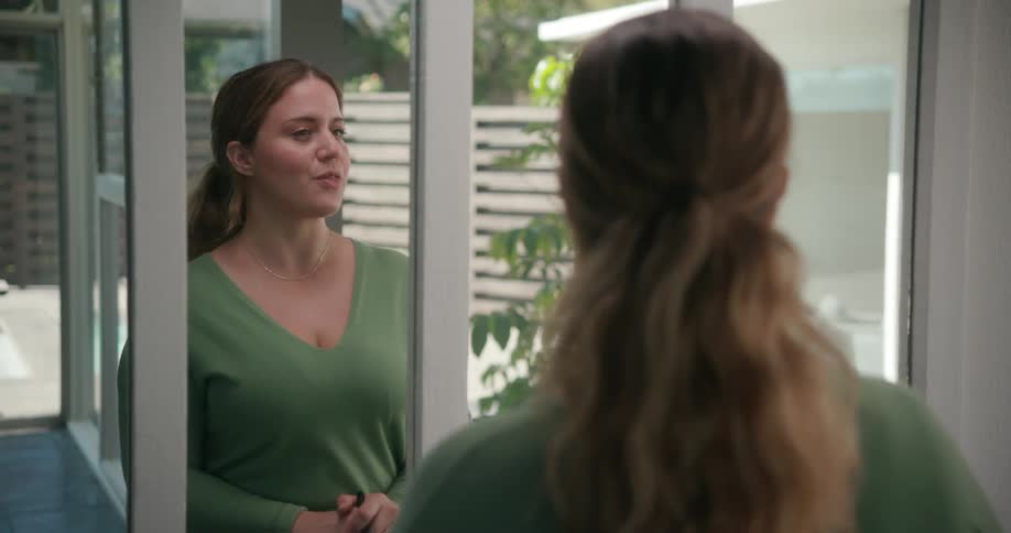 A woman looks at her reflection in a mirror as she rehearses lines from a script