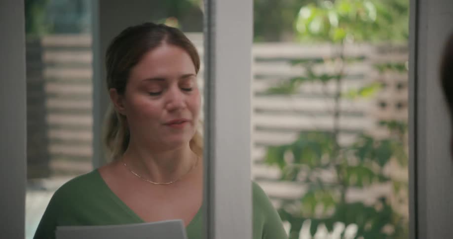 A woman stands in front of a mirror at home and practices a speech as she reads it