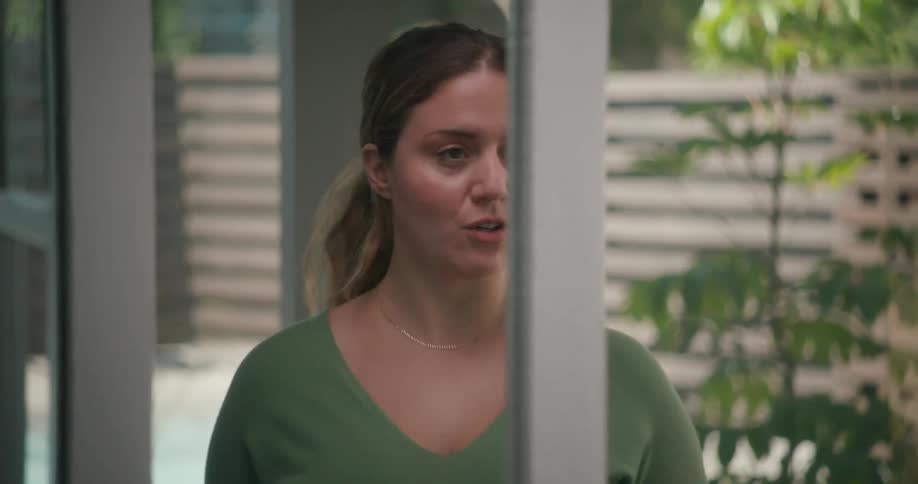 A woman holding a script rehearses her lines in front of her mirror at home