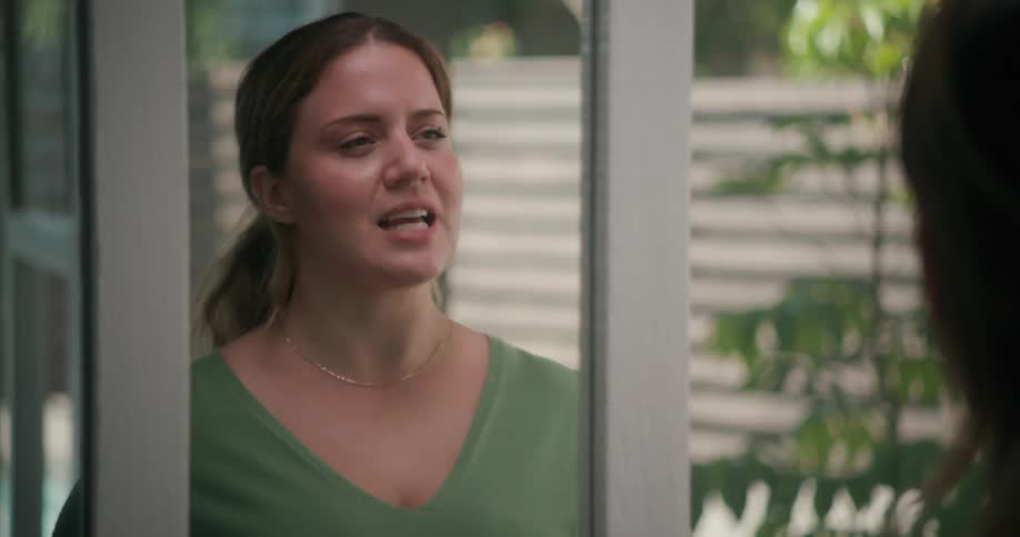 A woman is standing in front of a mirror speaking and holding her notes
