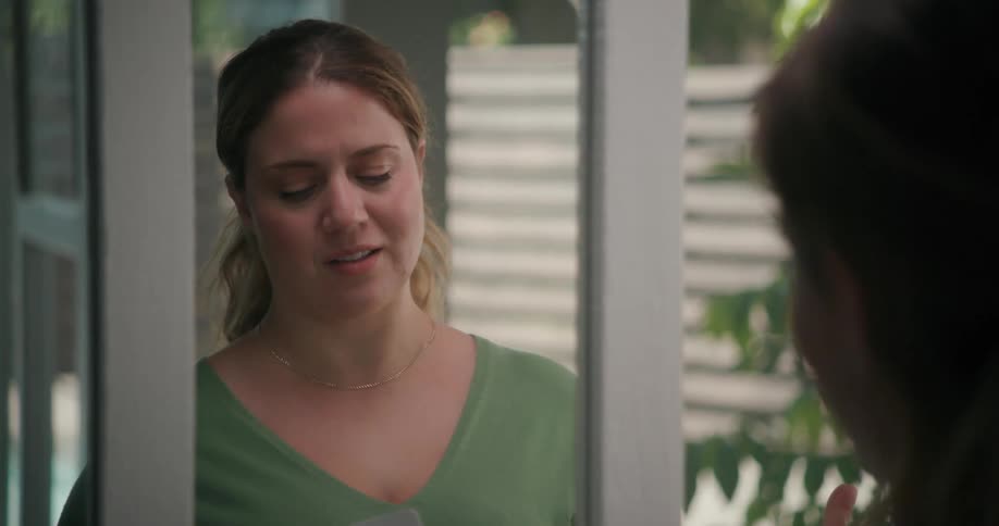 A woman taps her chin with a pen as she thinks then begins to practice her speech in a mirror