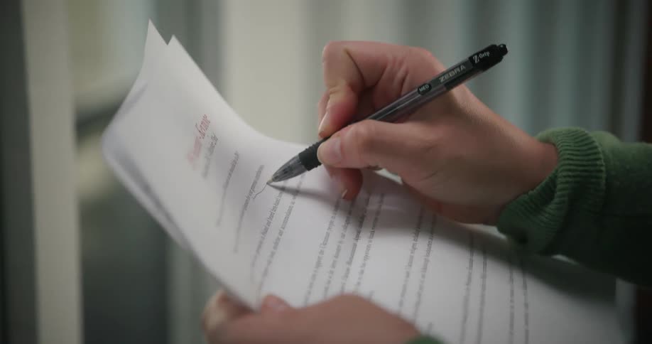 A woman underlines text on a piece of paper shes editing