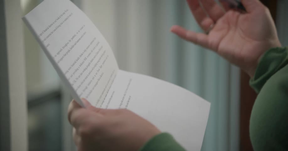 A woman is holding papers in her hands and marking them with a pen