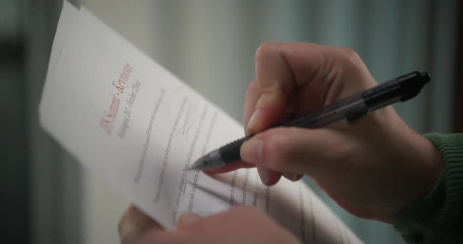 A woman is holding papers in her hands and marking them with a pen
