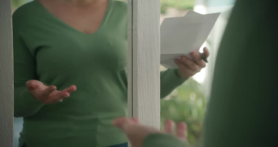 A woman edits and practices a keynote address in her mirror at home