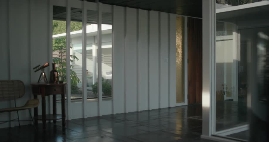 A neighborhood house is seen through the windows in a room