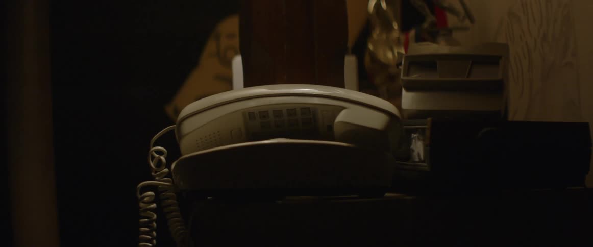 A phone is partially off the hook in a dark area