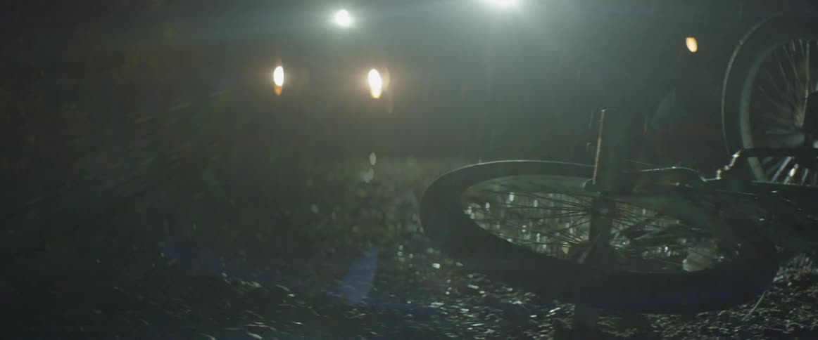 A wheel sits on the ground spinning as people walk over