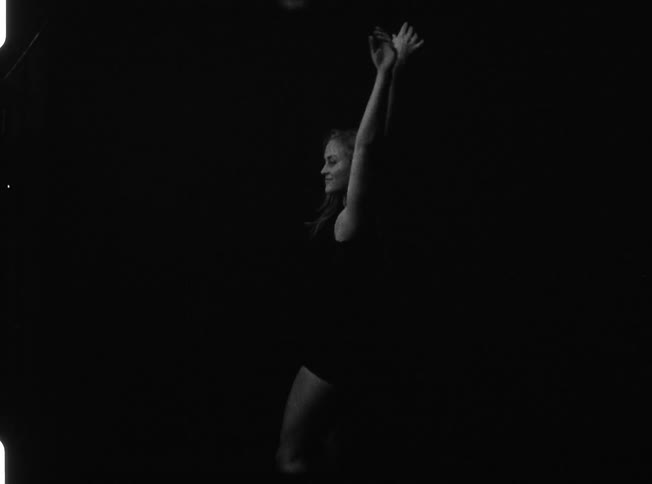 A woman is dancing in a dark area