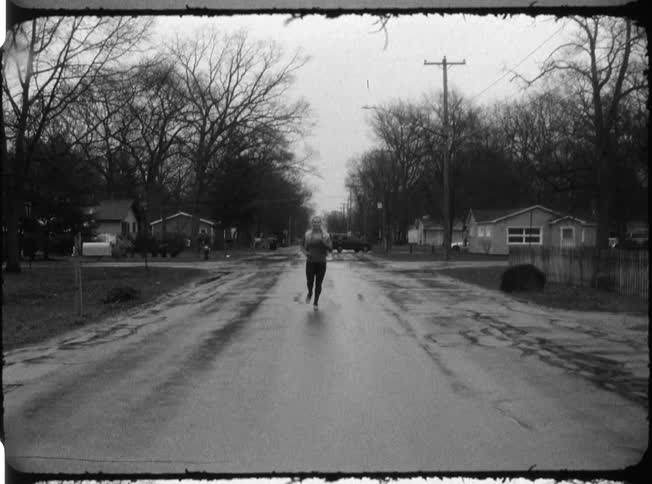 A woman jogs down a wet road