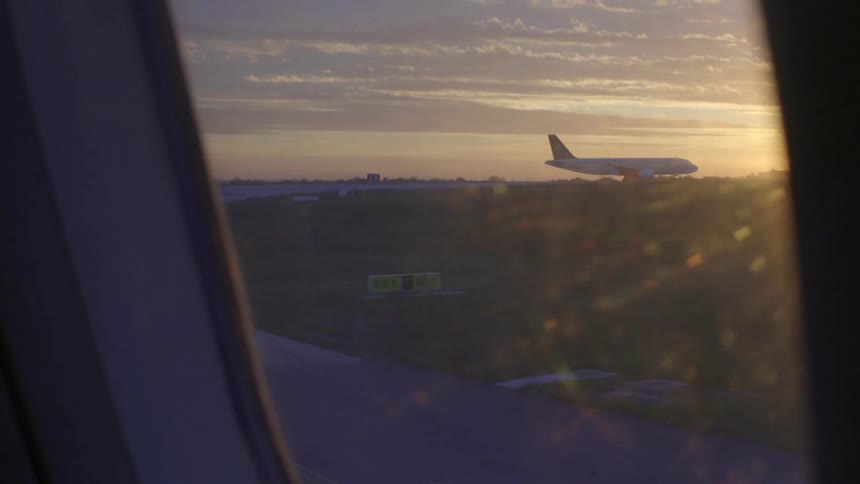 An airport as seen from the window of a plan that is currently landing at dusk