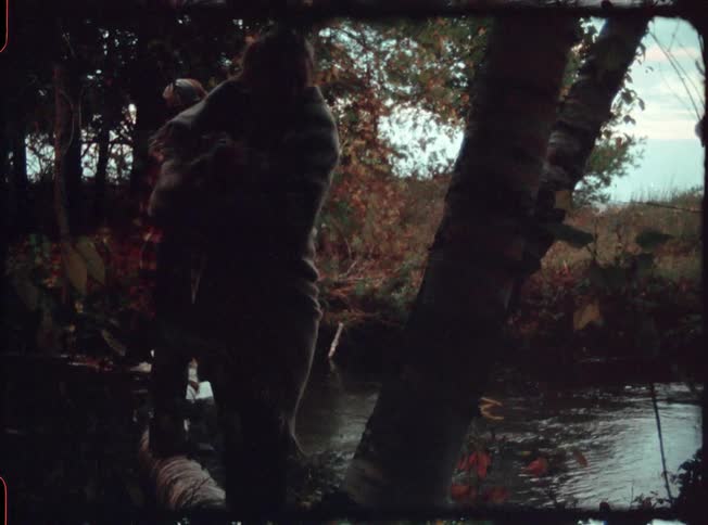 Two people climb along the side of a stream