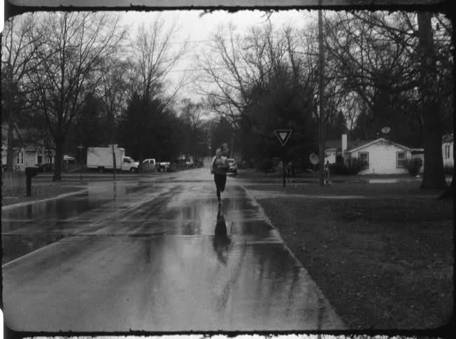 A woman jogs in a residential area while it rains