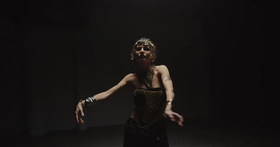 A female wearing a costume dancing against a black background