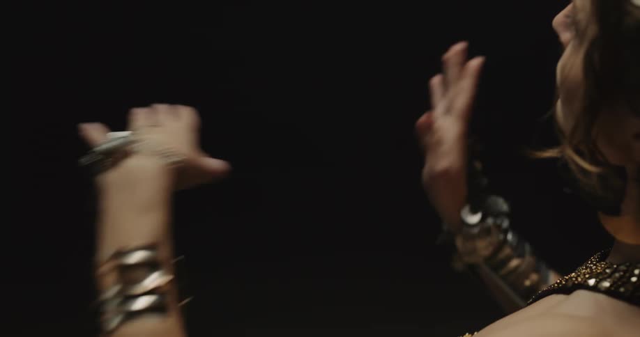Belly dancer wearing bedlahheadbands with golden coins golden necklace and bracelets performs dance on stage