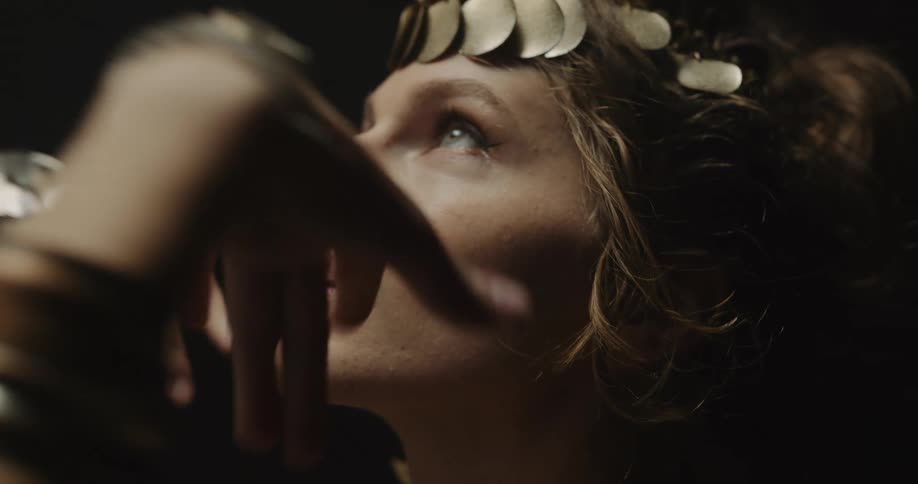 A woman wearing ornate jewelry making movements with her arms and hands