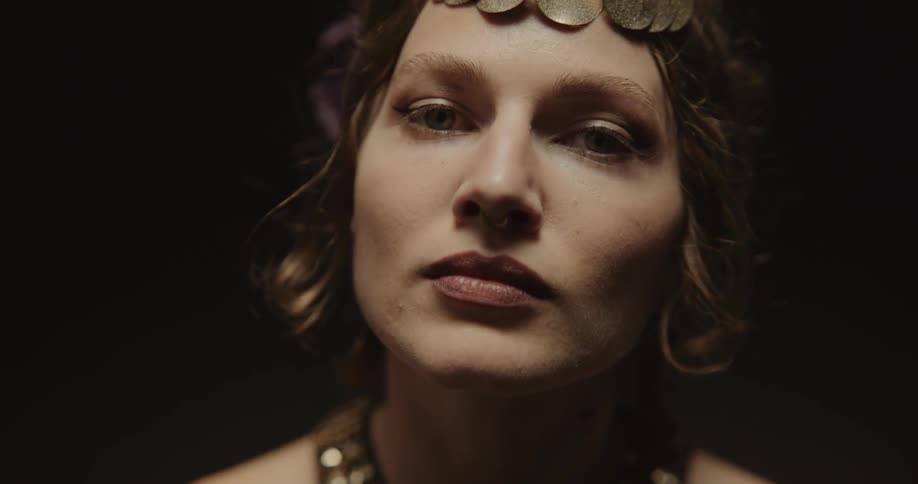 A woman poses in a gold headpiece and elaborate necklace
