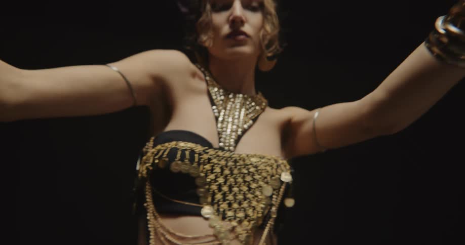 A woman waves her arms up and down while belly dancing