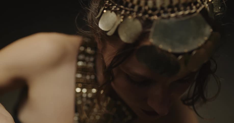 Belly dancer in bedlah headbands with golden coins golden necklace and bracelets performs dance and moves of the hips and torso on stage
