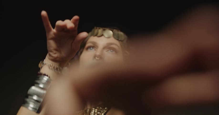 Belly dancer in bedlah headbands with golden coins golden necklace and bracelets performs dance and moves of the hips and torso on stage
