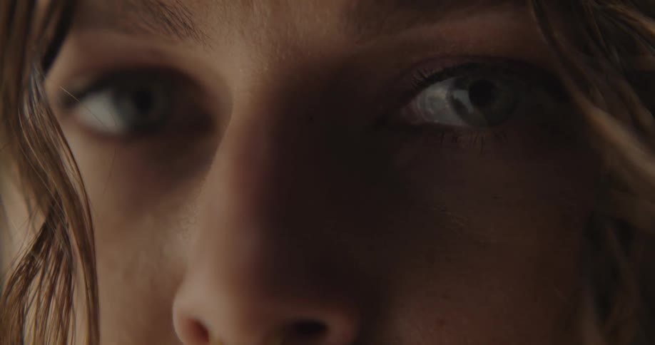 An extreme up close of a females face eyes shut at first and then open to look at the camera