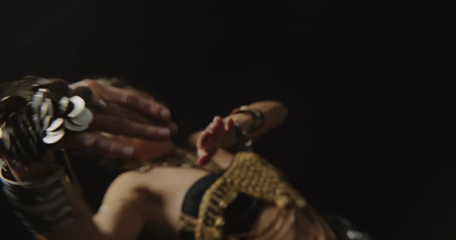 A woman performer waving her hands and body around while wearing eccentric jewelry