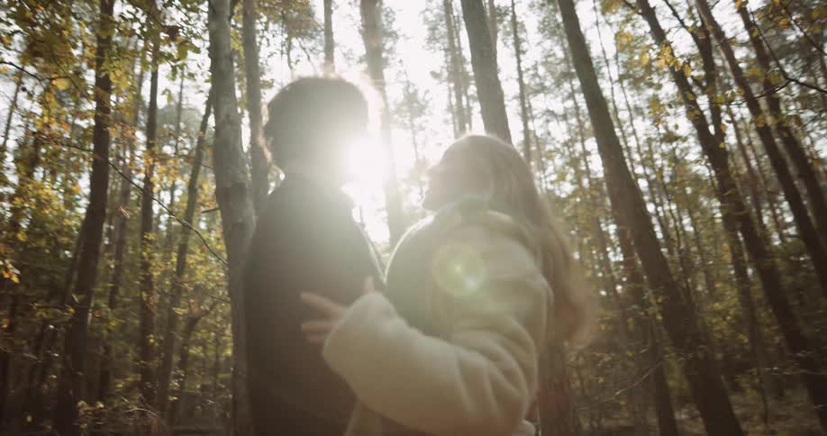 A man picks up his girlfriend and spins her around during a walk in the woods