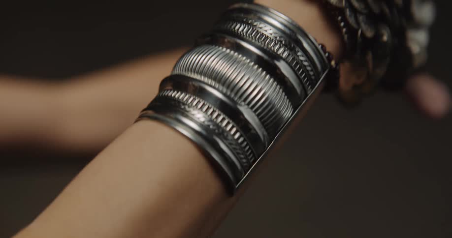 Belly dancers wearing bracelets with coins dances and moves her arms on the stage