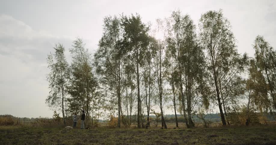Two people are hanging out in a wooded area together