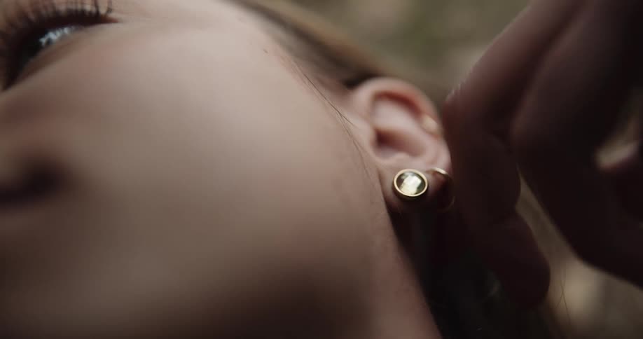 A person removing earrings from a girls ear