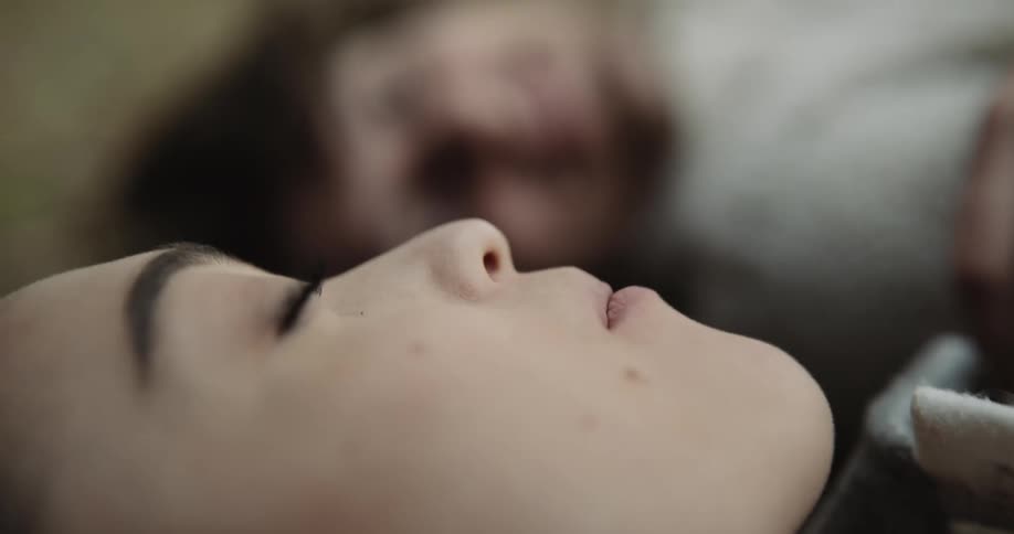 A man places food in a womans mouth as they are both laying on the ground