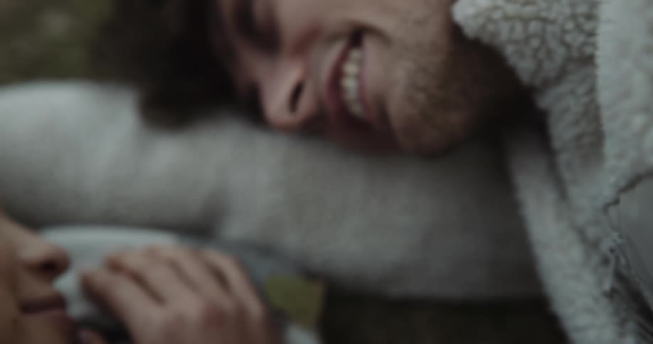 A teenage boy and girl flirting while lying outside on the ground