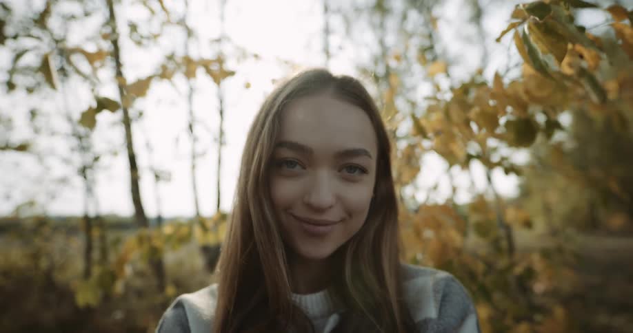 A female is smiling and sitting in a woodland area