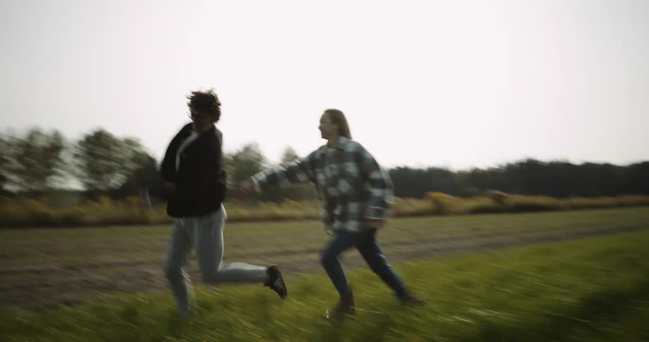 A couple kiss after running and chasing each other in a field
