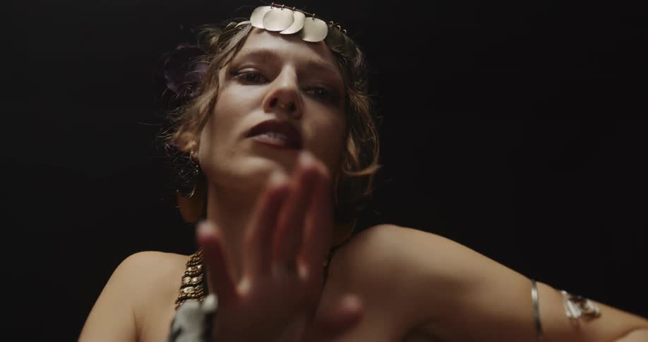 A woman slowly dancing and moving her arms and hands while wearing eccentric jewelry