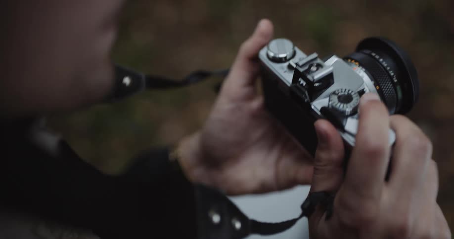 A man takes a photo while standing outside on fallen leaves