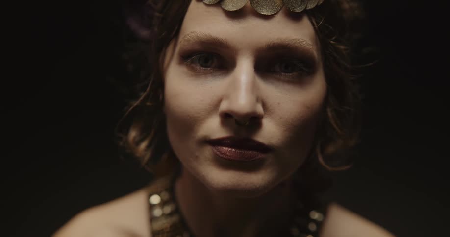 Belly dancer with nose piercing and headband with golden coins and necklace smiles at camera