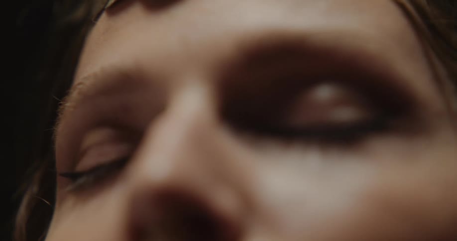 Light shines on a womans face as her eyes are closed and she is moving her her head and hands