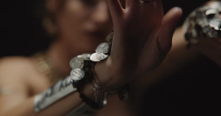 A woman in ornate jewelry doing dance poses with her hands