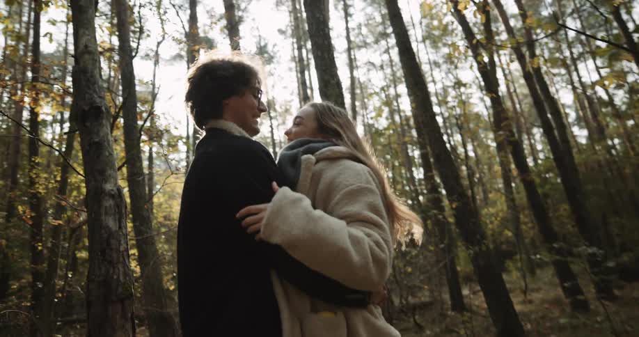 Boyfriend and girlfriend are kissing in a forest at dusk