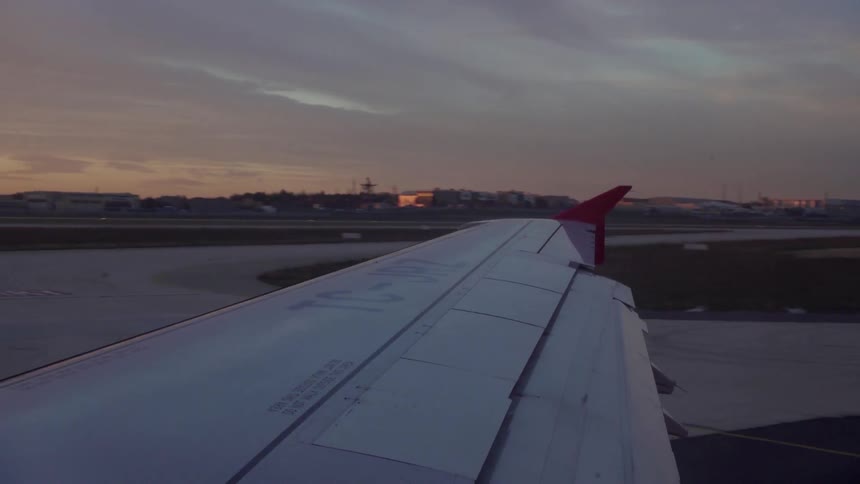 A plane is moving over a runway at sunset